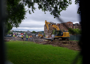 Construction crews watch as a section of pipe is laid into a trench along Waverly Avenue for the sewage line upgrade. 